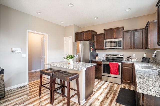 303 SE 14th St, Grimes, IA 50111 - kitchen with stainless steel appliances, light wood-style flooring, a kitchen island, dark brown cabinets, and recessed lighting