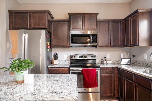303 SE 14th St, Grimes, IA 50111 - kitchen featuring stainless steel appliances, dark brown cabinets, and light stone countertops
