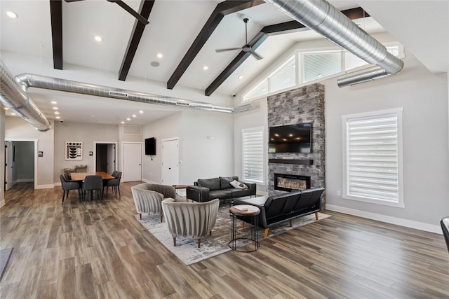 3213 NW Linwood Ln, Ankeny, IA 50023 - living area with ceiling fan, high vaulted ceiling, wood finished floors, a stone fireplace, and beam ceiling