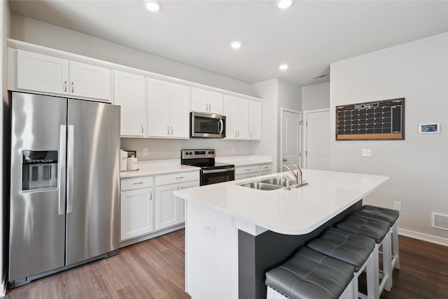 3213 NW Linwood Ln, Ankeny, IA 50023 - kitchen with stainless steel appliances, dark wood finished floors, a kitchen island with sink, white cabinetry, and recessed lighting