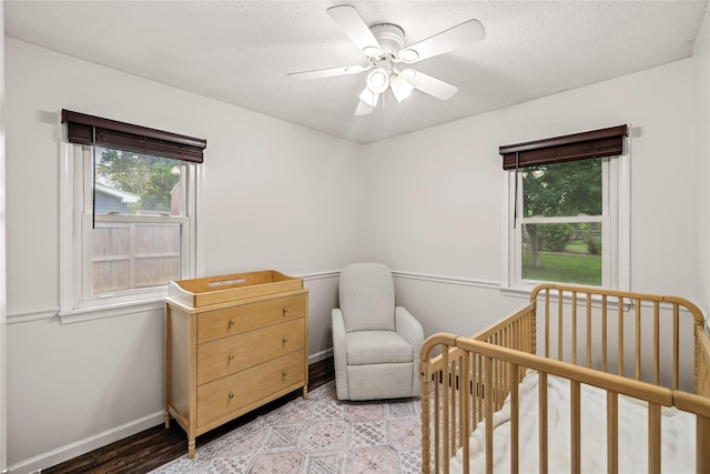 503 S Freeman St, Indianola, IA 50125 - bedroom featuring multiple windows, a nursery area, light wood-style floors, ceiling fan, and a textured ceiling