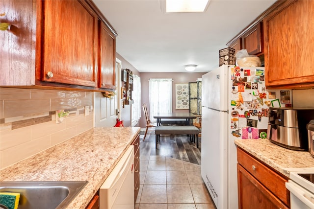 3935 8th St, Des Moines, IA 50313 - kitchen featuring white appliances, tasteful backsplash, and brown cabinetry