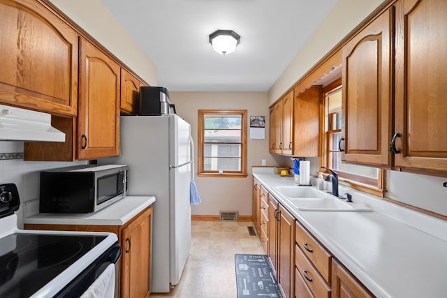 1232 Carrie Ave, Des Moines, IA 50315 - kitchen with range with electric stovetop, ventilation hood, black microwave, light countertops, and brown cabinetry