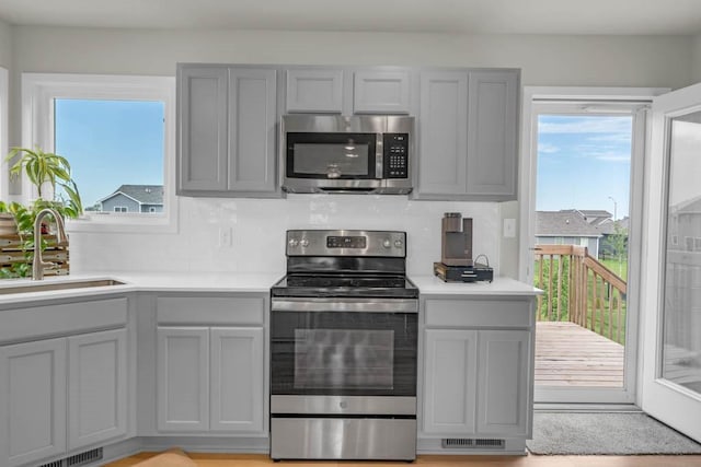 4412 NW 12th St, Ankeny, IA 50023 - kitchen with appliances with stainless steel finishes, gray cabinetry, light countertops, and tasteful backsplash