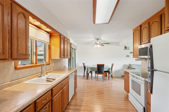 106 NW Scott St, Ankeny, IA 50023 - kitchen with white appliances, brown cabinetry, backsplash, a ceiling fan, and light wood-style floors