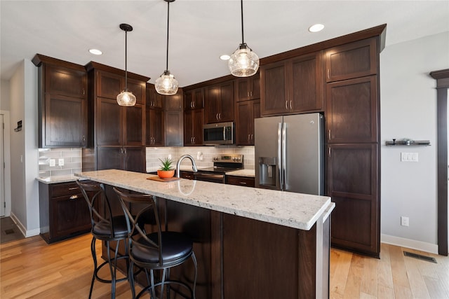 1609 NW Prairie Creek Dr, Grimes, IA 50111 - kitchen featuring appliances with stainless steel finishes, decorative backsplash, recessed lighting, dark brown cabinets, and light wood-style flooring