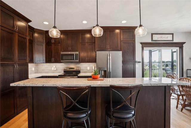 1609 NW Prairie Creek Dr, Grimes, IA 50111 - kitchen featuring appliances with stainless steel finishes, dark brown cabinetry, decorative backsplash, light stone countertops, and recessed lighting