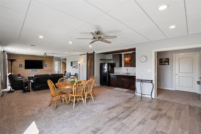 1609 NW Prairie Creek Dr, Grimes, IA 50111 - dining room with a barn door, ceiling fan, light wood finished floors, recessed lighting, and wooden walls