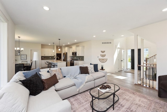 4774 172nd Way, Urbandale, IA 50323 - living area featuring light wood-style flooring, recessed lighting, stairs, and a chandelier