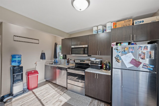 714 E 27th St, Des Moines, IA 50317 - kitchen with appliances with stainless steel finishes, light countertops, light wood finished floors, and dark brown cabinetry