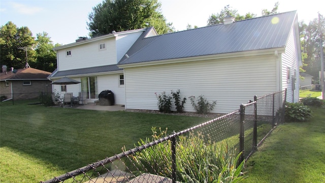 1401 N Grant St, Knoxville, IA 50138 - back of property featuring a metal roof, a fenced backyard, and a chimney