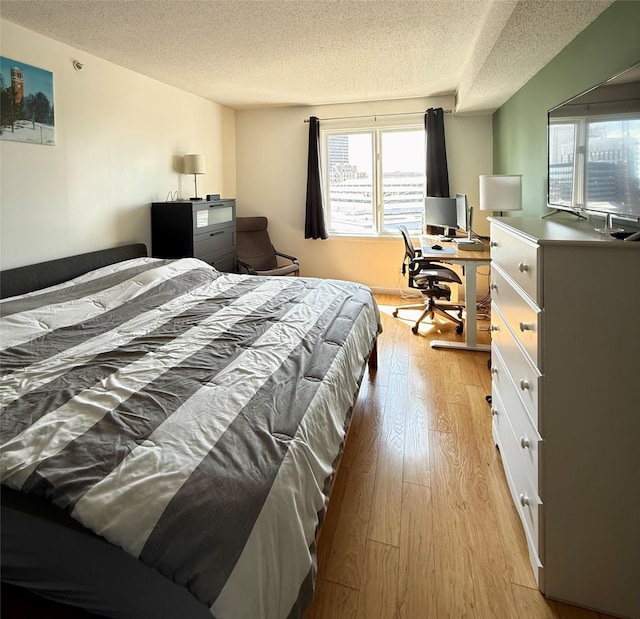 300 Walnut St Unit 1505, Des Moines, IA 50309 - bedroom featuring a textured ceiling, light wood-style flooring, multiple windows, and an office area
