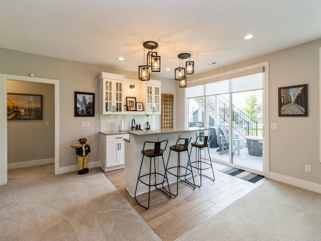 2013 Autumn Blaze Dr, Norwalk, IA 50211 - kitchen with a breakfast bar, white cabinetry, a center island, glass insert cabinets, and recessed lighting