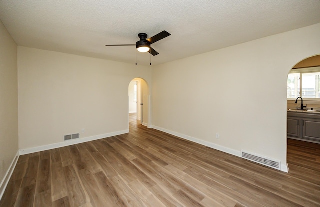3912 53rd St, Des Moines, IA 50310 - empty room with arched walkways, wood finished floors, a ceiling fan, and a textured ceiling