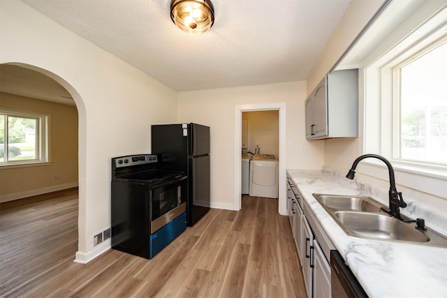 3912 53rd St, Des Moines, IA 50310 - kitchen featuring stainless steel range with electric cooktop, washer and clothes dryer, arched walkways, light wood-style floors, and freestanding refrigerator