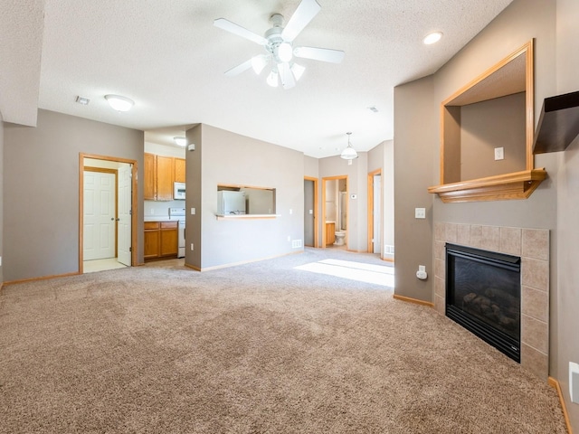 1106 N 6th St Unit 42, Indianola, IA 50125 - unfurnished living room featuring carpet flooring, a textured ceiling, a ceiling fan, and a tiled fireplace