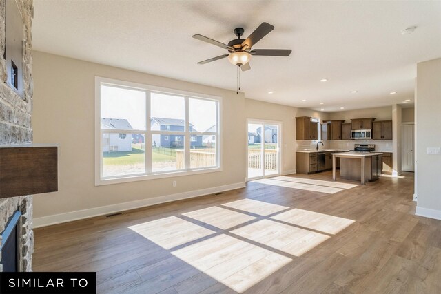 3601 NW 27th St, Ankeny, IA 50023 - unfurnished living room with a stone fireplace, light wood-style floors, ceiling fan, and recessed lighting