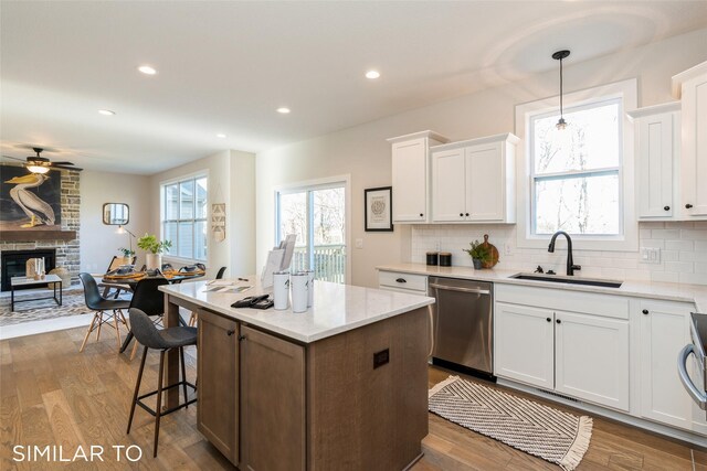 3601 NW 27th St, Ankeny, IA 50023 - kitchen featuring stainless steel dishwasher, a large fireplace, a kitchen island, white cabinets, and backsplash