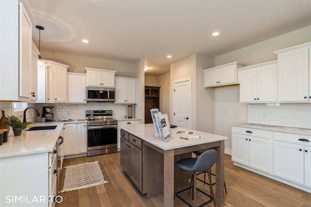 3601 NW 27th St, Ankeny, IA 50023 - kitchen featuring appliances with stainless steel finishes, wood finished floors, white cabinetry, and recessed lighting