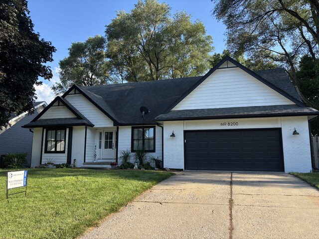 8200 Goodman Dr, Urbandale, IA 50322 - view of front of house with a garage, driveway, a front yard, roof with shingles, and brick siding