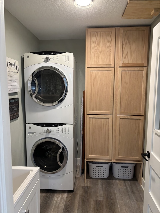 8200 Goodman Dr, Urbandale, IA 50322 - laundry area featuring stacked washer / dryer, dark wood finished floors, cabinet space, and a textured ceiling