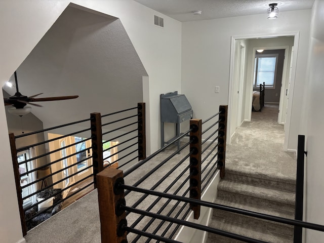 8200 Goodman Dr, Urbandale, IA 50322 - stairway featuring carpet floors, ceiling fan, and a textured ceiling