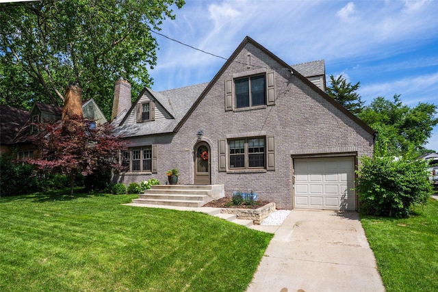 5625 Kingman Ave, Des Moines, IA 50311 - tudor house with a garage, concrete driveway, a front yard, a chimney, and brick siding