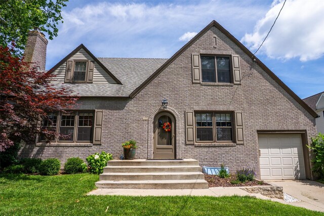 5625 Kingman Ave, Des Moines, IA 50311 - tudor-style house with brick siding, an attached garage, and concrete driveway