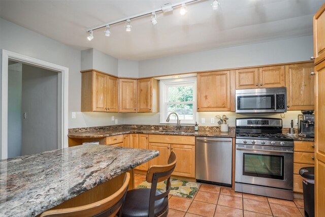 5625 Kingman Ave, Des Moines, IA 50311 - kitchen featuring appliances with stainless steel finishes, rail lighting, dark stone countertops, and light tile patterned floors