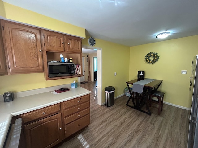 607 E Jasper St, Pleasantville, IA 50225 - kitchen with appliances with stainless steel finishes, wood finished floors, light countertops, and brown cabinets