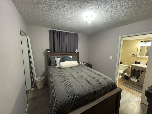607 E Jasper St, Pleasantville, IA 50225 - bedroom featuring light wood-type flooring, ensuite bath, and a textured ceiling