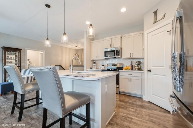 2401 E 50th St, Des Moines, IA 50317 - kitchen with stainless steel appliances, a breakfast bar area, tasteful backsplash, dark wood-style floors, and light countertops