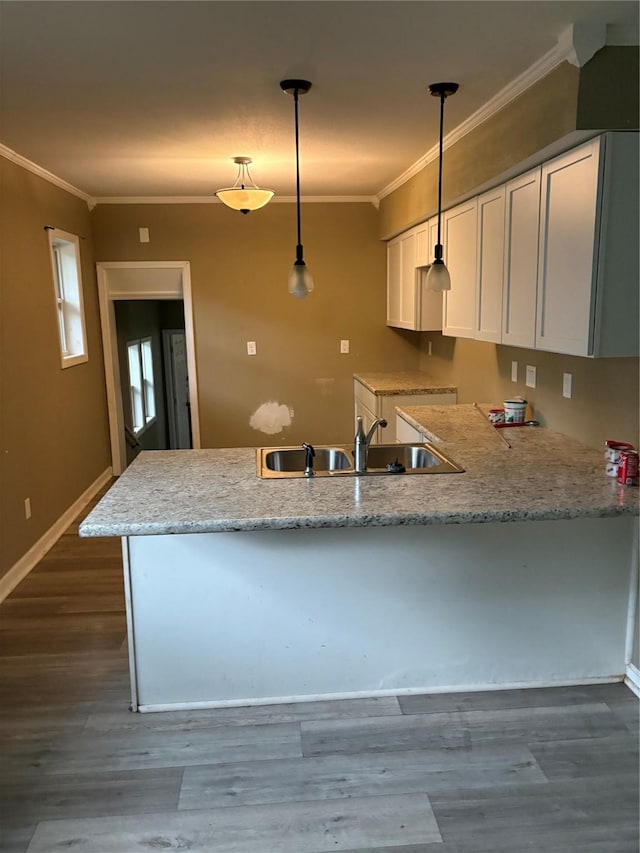 3112 52nd St, Des Moines, IA 50310 - kitchen featuring a peninsula, ornamental molding, white cabinetry, dark wood-style flooring, and pendant lighting