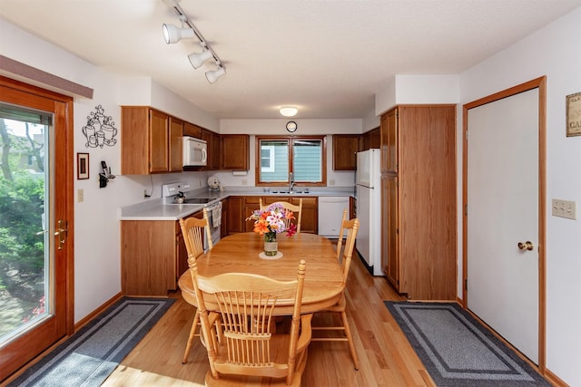 3806 Columbine Ave, Ames, IA 50010 - kitchen featuring white appliances, brown cabinetry, light wood-style floors, light countertops, and rail lighting