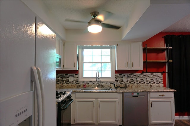 609 E Filmore St, Winterset, IA 50273 - kitchen with stainless steel appliances, decorative backsplash, white cabinets, and ceiling fan