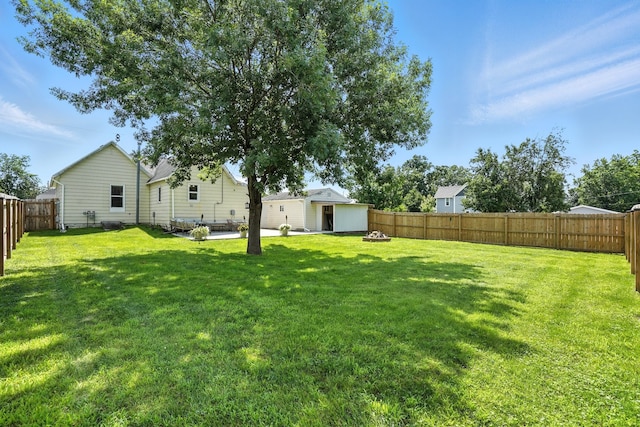 510 Maple Ave, Woodward, IA 50276 - fenced backyard featuring a fire pit, an outbuilding, and a patio