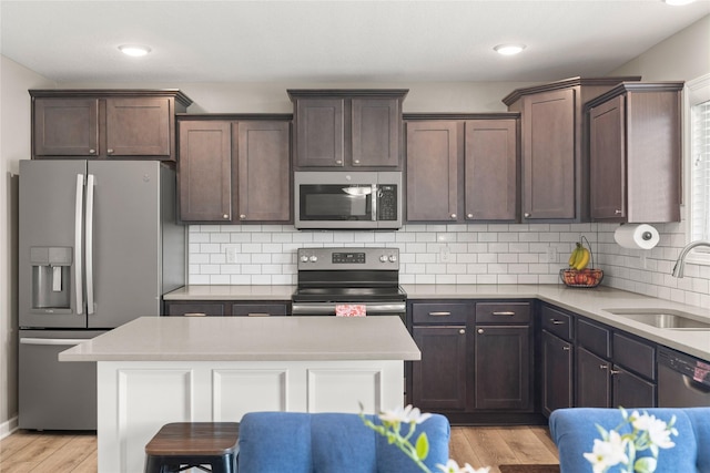 2718 NW 23rd St, Ankeny, IA 50023 - kitchen with stainless steel appliances, dark brown cabinets, light wood finished floors, decorative backsplash, and light countertops