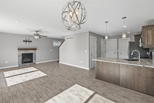 2017 NE Heritage Dr, Grimes, IA 50111 - kitchen featuring ceiling fan, light wood finished floors, light stone countertops, a peninsula, and decorative light fixtures