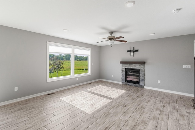 2017 NE Heritage Dr, Grimes, IA 50111 - unfurnished living room featuring a ceiling fan, light wood-style flooring, and a stone fireplace