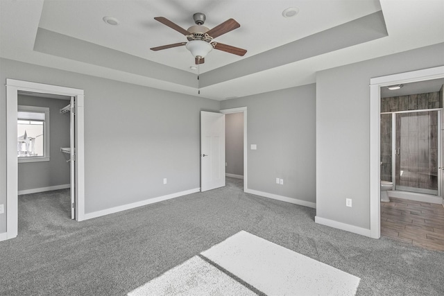 2017 NE Heritage Dr, Grimes, IA 50111 - unfurnished bedroom featuring a raised ceiling, carpet, a spacious closet, ensuite bathroom, and a ceiling fan