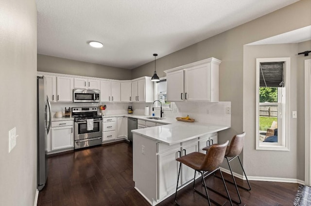 145 SE Kellerman Ln, Waukee, IA 50263 - kitchen with appliances with stainless steel finishes, a peninsula, white cabinetry, and decorative backsplash