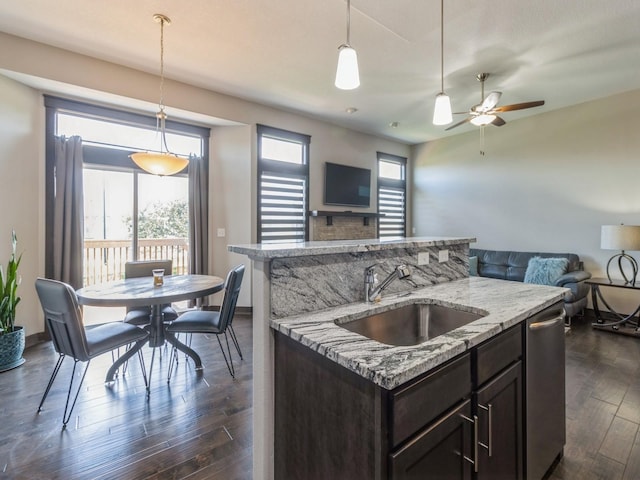 8955 Jamison Dr, West Des Moines, IA 50266 - kitchen with open floor plan, stainless steel dishwasher, dark brown cabinetry, dark wood-style flooring, and decorative light fixtures