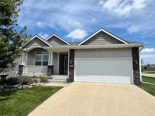 8955 Jamison Dr, West Des Moines, IA 50266 - view of front of home with stone siding, concrete driveway, a garage, covered porch, and a front lawn
