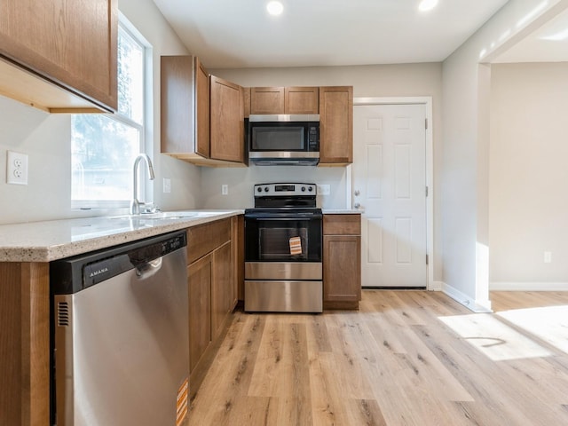 404 S B St, Indianola, IA 50125 - kitchen featuring stainless steel appliances, light wood-style floors, brown cabinetry, recessed lighting, and light stone counters