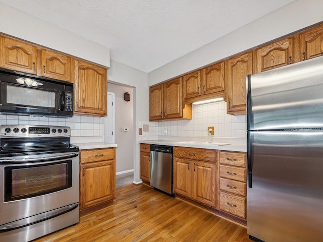 4408 66th St, Urbandale, IA 50322 - kitchen with stainless steel appliances, light countertops, light wood-style floors, and backsplash