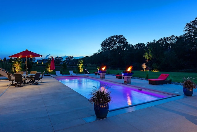 11174 NW 108th Ct, Granger, IA 50109 - pool at dusk with a fire pit, a patio area, an outdoor pool, and a mountain view