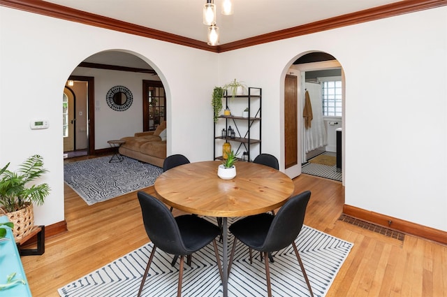 2220 York St, Des Moines, IA 50316 - dining room with light wood-style flooring, arched walkways, and crown molding