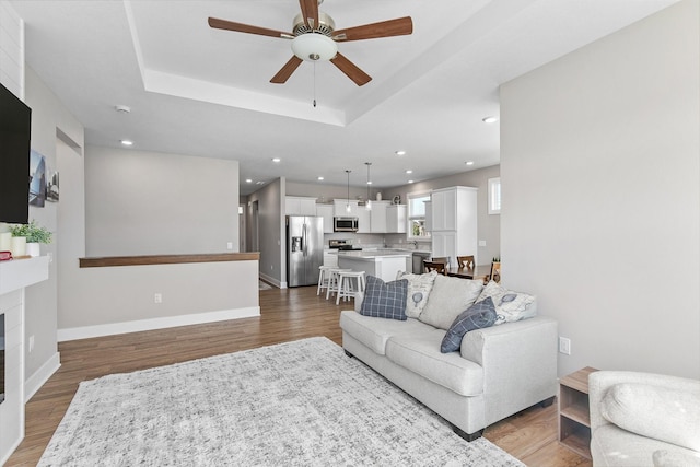 2845 SE Bluestem Dr, Waukee, IA 50263 - living room with ceiling fan, a raised ceiling, wood finished floors, recessed lighting, and a fireplace
