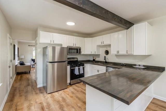 3901 Lawnwoods Dr, Des Moines, IA 50310 - kitchen featuring stainless steel appliances, dark countertops, a peninsula, beam ceiling, and white cabinets