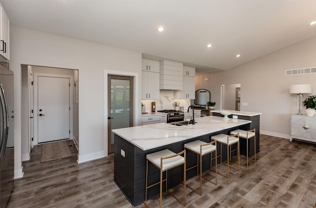 16320 Northpark Dr, Urbandale, IA 50323 - kitchen with a large island, white cabinets, dark wood finished floors, a kitchen breakfast bar, and vaulted ceiling